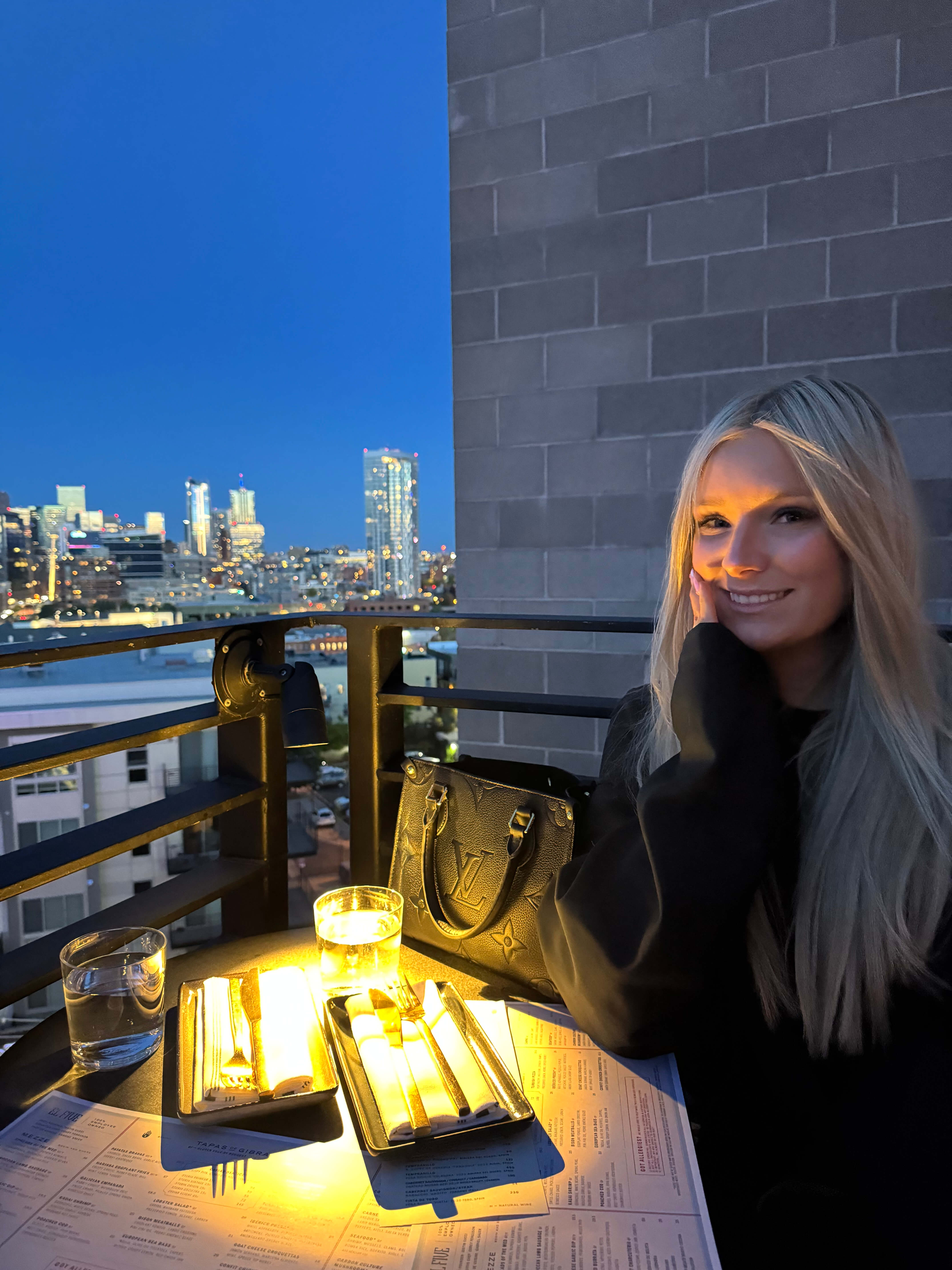 Karianna, owner and hairstylist at Kari & Co. Hair Studio, smiling with the Denver skyline behind her